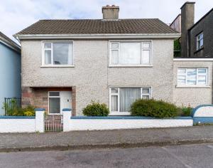 a brick house with white windows on a street at Sneem Townhouse in Sneem