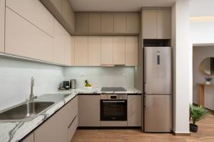 a kitchen with white cabinets and a stainless steel refrigerator at Kitron Blue Seaside Luxury Apartment in Agios Nikolaos