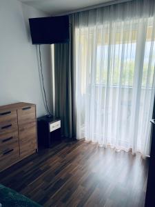 a bedroom with a dresser and a large window at Apartament Atrium Sarbinowo in Sarbinowo +17 photos