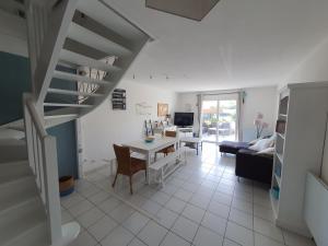 a living room with a staircase and a table at Villa Belle Ile in Saint-Pierre-dʼOléron