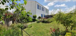 a white building with blue windows in a garden at Villa Belle Ile in Saint-Pierre-dʼOléron