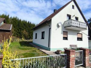 a white house with a balcony and a fence at FeWo Rina in Pottenstein +18 photos