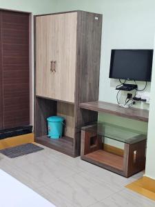 a living room with a tv and a wooden cabinet at Arya Palace in Phulabāni