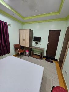 a bedroom with a bed and a desk and a television at Arya Palace in Phulabāni