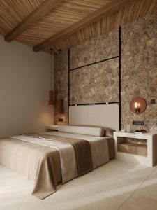 a bedroom with a large bed and a stone wall at Salt and stone suites in Vrachonisída touArchangélou +29 photos
