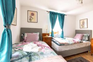 two beds in a room with blue curtains at Herbal Garden Resort Plahtica in Jurklošter