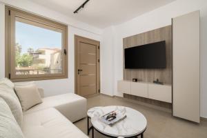 a living room with a white couch and a tv at D & D Apartments in Kassandra