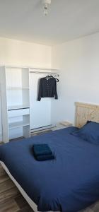 a bedroom with a blue bed and a shirt hanging on a wall at Appartement T4 proche gare in Guingamp