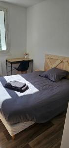 a bed with a blue blanket and a desk in a room at Appartement T4 proche gare in Guingamp +5 photos