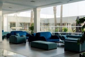 a lobby with blue furniture and palm trees at One Resort Jockey Monastir in Monastir