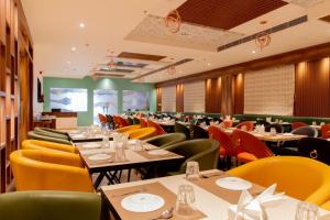 a restaurant with tables and colorful chairs and tablesktop at Hotel Avenue 30 in Lucknow