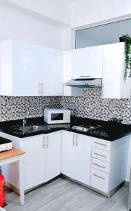 a kitchen with white cabinets and a black counter top at Coral Beach Hotel Punta Cana in Punta Cana