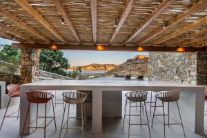 a kitchen with a bar with stools and a view at Villa Evita Panormos private pool & jacouzzi in Mykonos