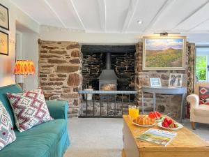 a living room with a green couch and a stone fireplace at Whitley Farm Molland in Molland