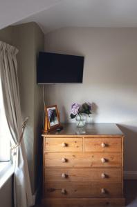 a bedroom with a dresser with a television on the wall at Lingmoor in Windermere +25 photos
