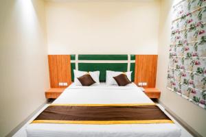a bedroom with a white bed with a green headboard at Hotel Avenue 30 in Lucknow +26 photos
