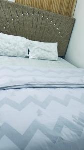 a bed with a wooden headboard and white sheets and pillows at Osim bnb 2 in Arusha