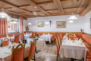 a dining room with tables and chairs with white tablecloths at Hotel & Residence Sylvanerhof in Chiusa