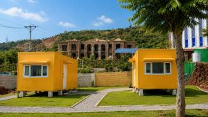 two yellow modular homes in front of a building at The Onyx by 7 Valleys in Islamabad