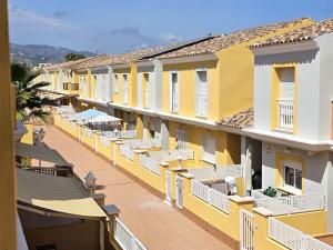 a row of yellow buildings with tables and umbrellas at Casa Althaya in Alcalà de Xivert