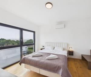 a white bedroom with a bed and a large window at Vila Volme in Banjole +12 photos
