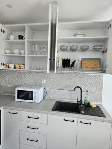 a white kitchen with a sink and a microwave at marius in Chiajna