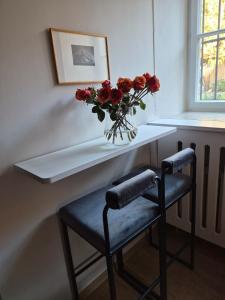 a vase of flowers on a shelf with two stools at Entzückendes Studio in historischer Villa in Aschau