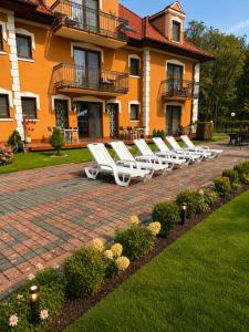 a row of white lounge chairs in front of a building at Pałacyk in Międzywodzie +99 photos