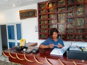 a woman sitting at a table in a room at Madibak Hotel Limbe in Limbe