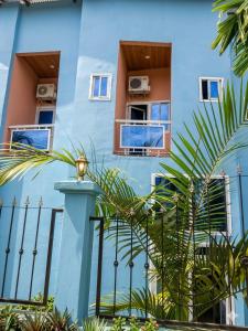 a blue building with palm trees in front of it at Madibak Hotel Limbe in Limbe