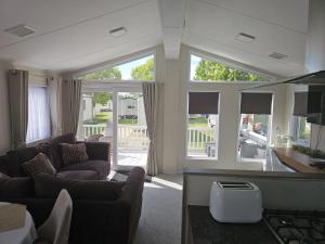 a living room with two couches and a kitchen with windows at Bwr27 in East Mersea