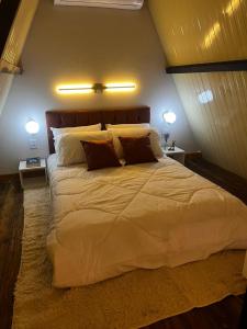 a bedroom with a large white bed with two lights at Chalés Alto Caparaó in Caparaó Velho