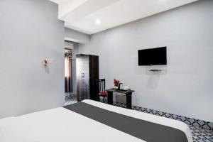 a white room with a bed and a flat screen tv at Hotel Sundari in Guwahati