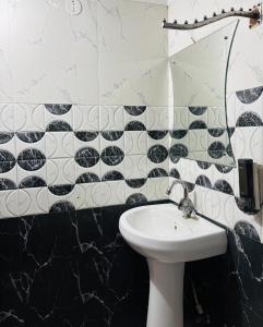 a bathroom with a sink and black and white tiles at Hotel Sundari in Guwahati