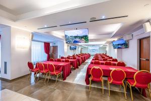a conference room with red tables and chairs and screens at Cardinal Hotel St. Peter in Rome