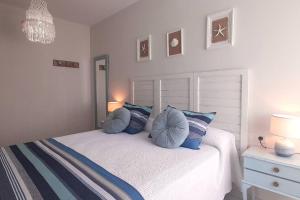 a bedroom with a white bed with blue pillows at Apartamento Playa in Burela de Cabo
