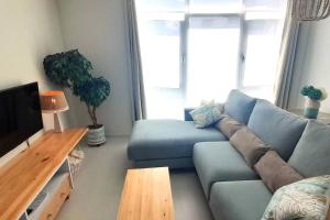 a living room with a blue couch and a tv at Apartamento Playa in Burela de Cabo