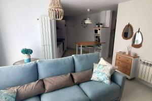 a blue couch in a living room with a kitchen at Apartamento Playa in Burela de Cabo
