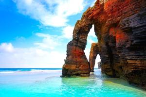 an arch in the rocks on the beach at Apartamento Playa in Burela de Cabo
