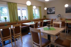a restaurant with wooden tables and chairs and windows at Kurbad St Martin in Bad Kohlgrub