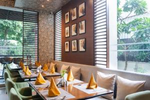 a row of tables in a restaurant with yellow napkins at Udman Hotel Panchshila Park in New Delhi