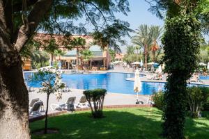 a pool at a resort with chairs and a umbrella at Grand Mogador Agdal & Spa in Marrakesh