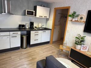 a kitchen with white cabinets and a couch in a room at Pension EdHeLo in Barby