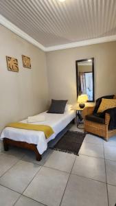 a bedroom with a bed and a mirror and a chair at Ikaya Accommodation PSJ in Port St. Johns
