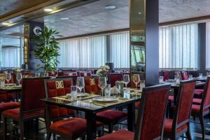 ein Esszimmer mit Tischen, Stühlen und Fenstern in der Unterkunft Prezident Hotel Novi Sad - Outdoor Pool & Spa in Novi Sad