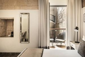 a bedroom with a bed and a mirror and a chair at 66 Saint Paul's & Spa in Valletta