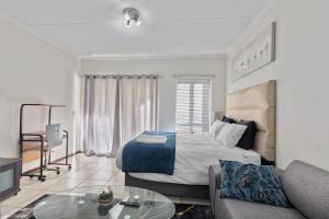 a bedroom with a bed and a couch and a table at Spacious Studio Fourways Sandton - Self Check-in in Sandton