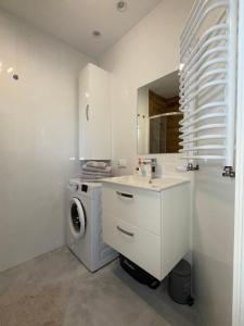 a white bathroom with a washing machine and a sink at Mieszkanie - Apartament in Dąbrowa