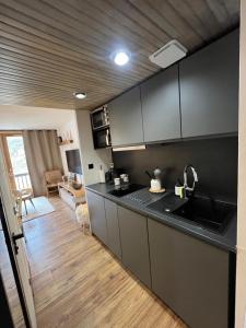 a kitchen with a black counter top and wooden floors at Studio Auron 4 couchages in Saint-Étienne-de-Tinée