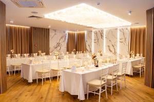 a conference room with tables and chairs with white tablecloths at Aqua Hotel in Burgas